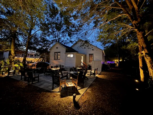 The Ash Street courtyard glowing beneath its oak tree at dusk