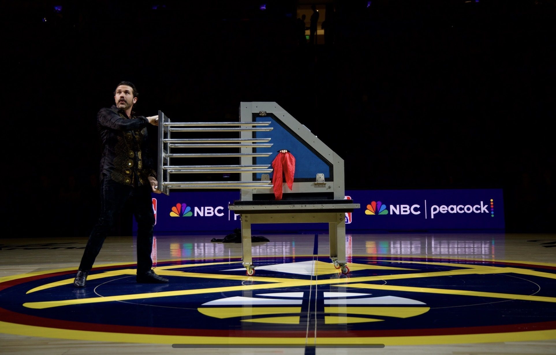 Magician JP Wilson and assistant performing a halftime illusion at a Denver Nuggets game