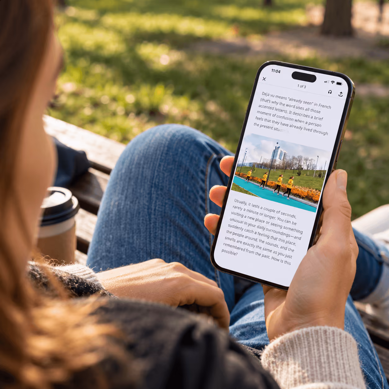 Woman on a park bench reading a Nerdish article about déjà vu on her phone