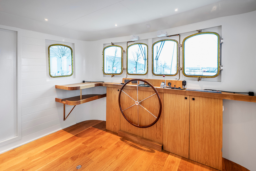 A finished houseboat interior with a ship's wheel and wooden cabinetry