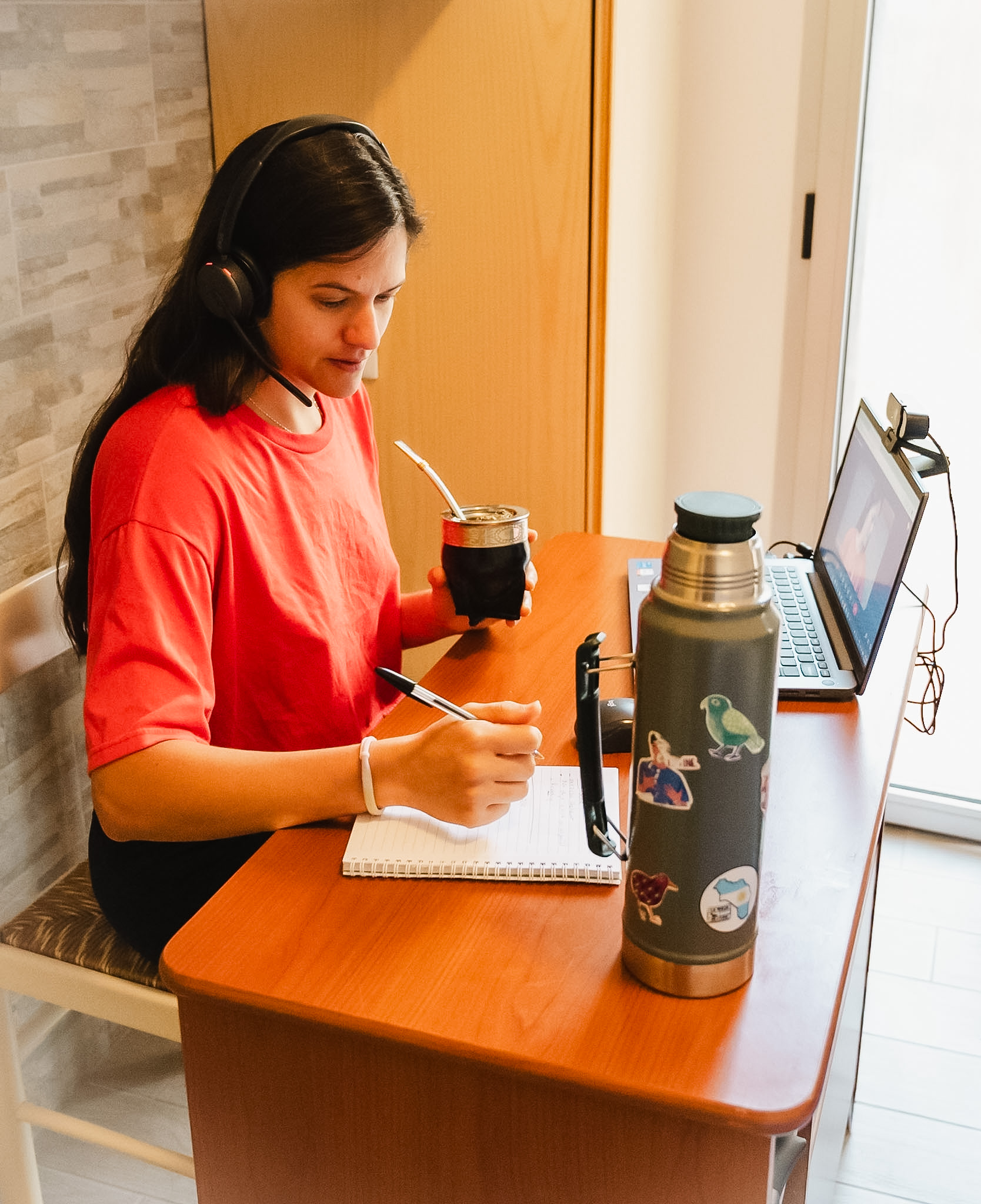 Pamela teaching an online lesson from her desk, with headphones and a cup of yerba mate