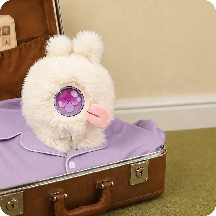 A white Mumuland companion on a suitcase