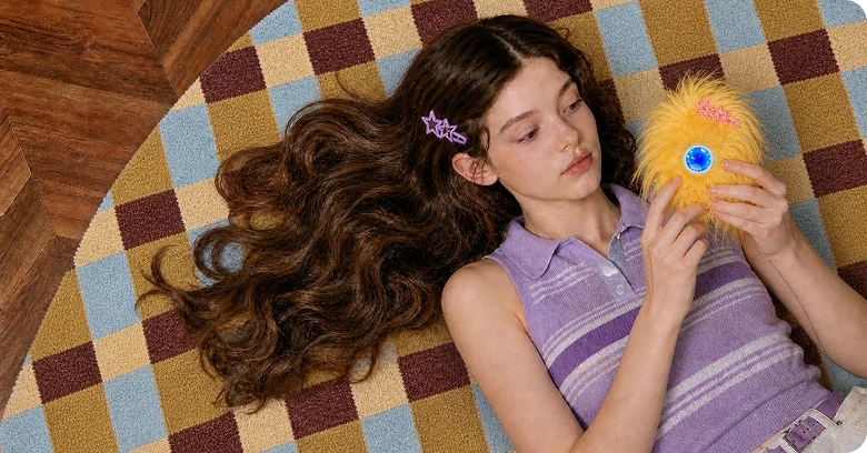 A girl lying on a checked rug with her yellow Mumuland companion