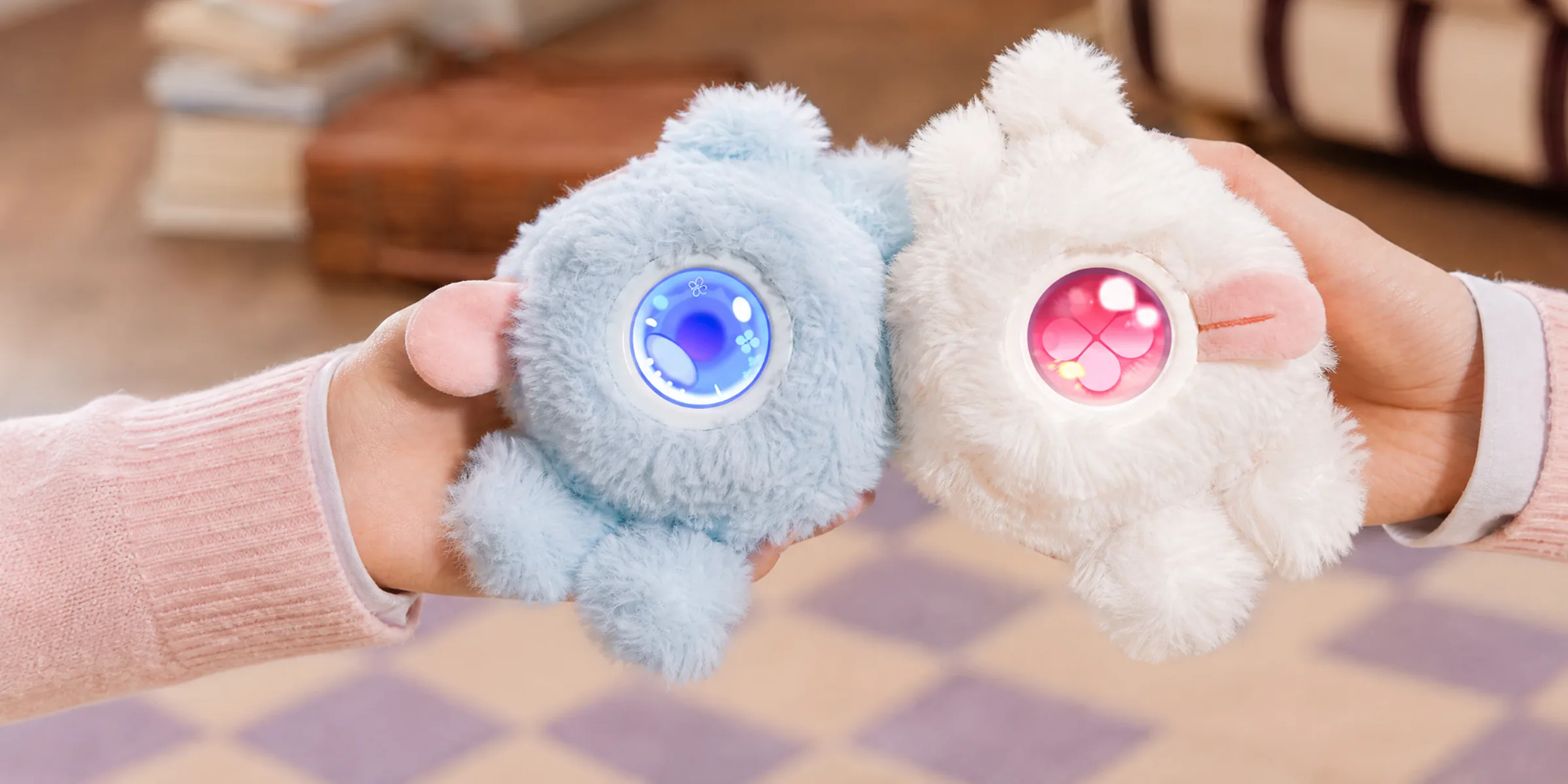 Two hands holding a blue and a white Mumuland companion