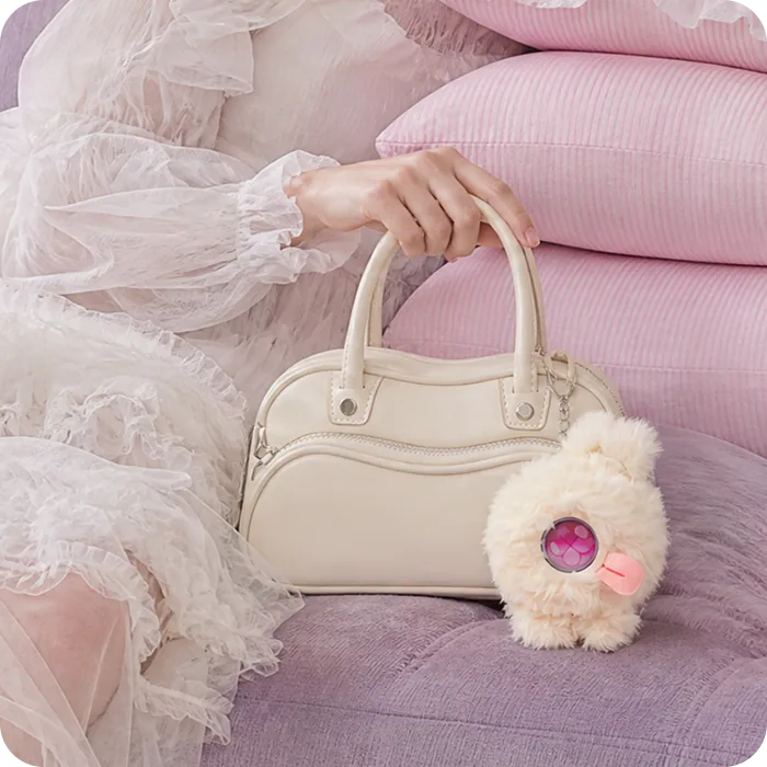 A white Mumuland companion clipped to a pink handbag