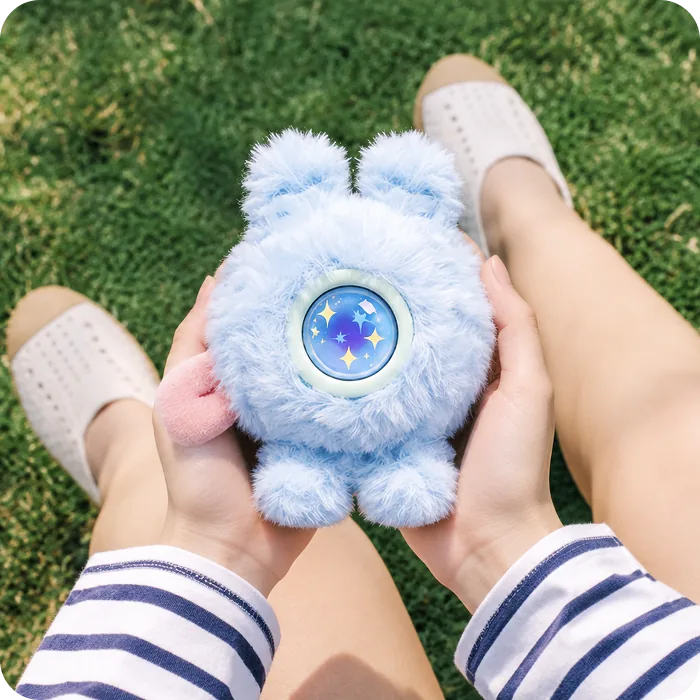 Friends holding a blue Mumuland companion on the grass