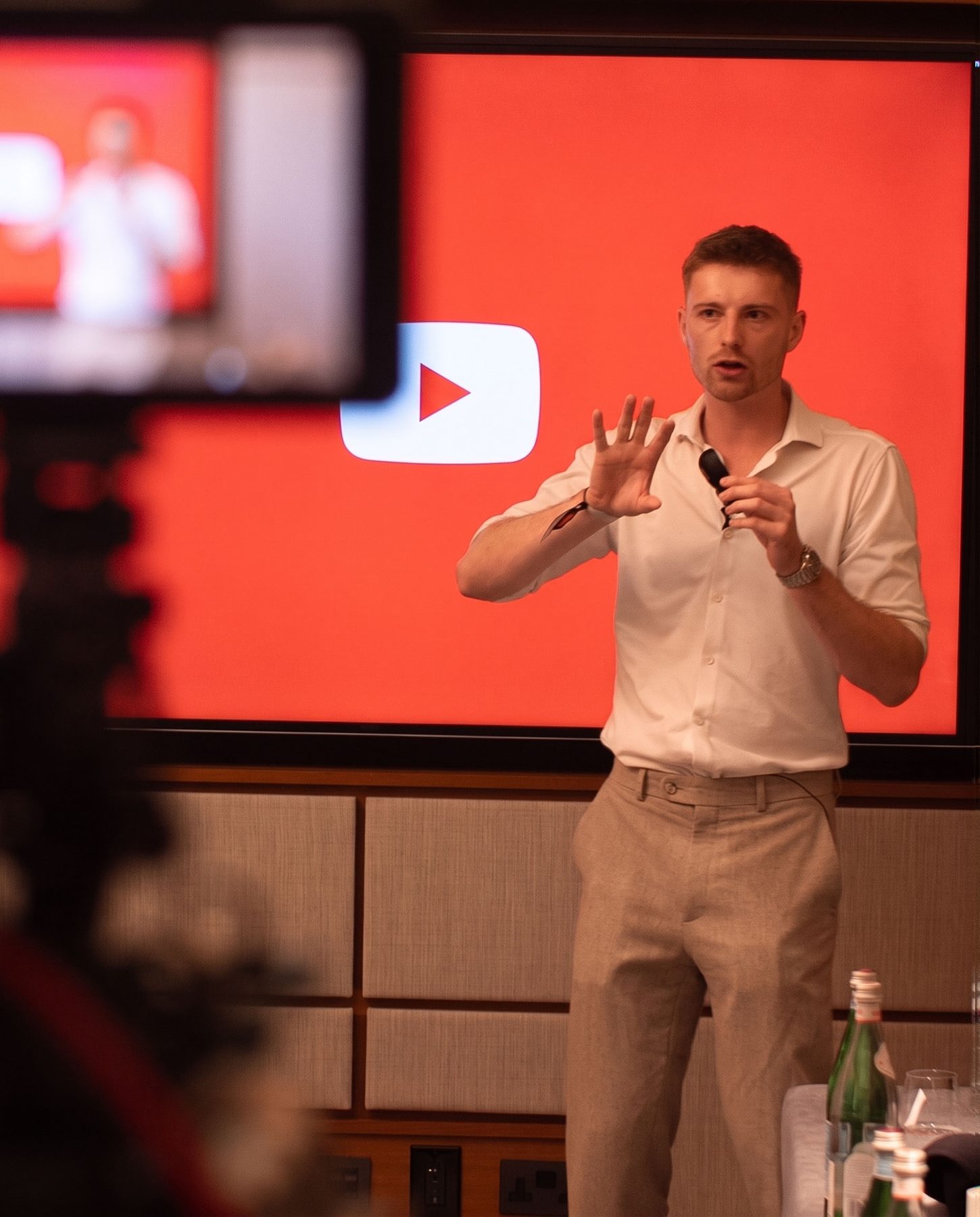 Oscar speaking on stage in front of a YouTube logo