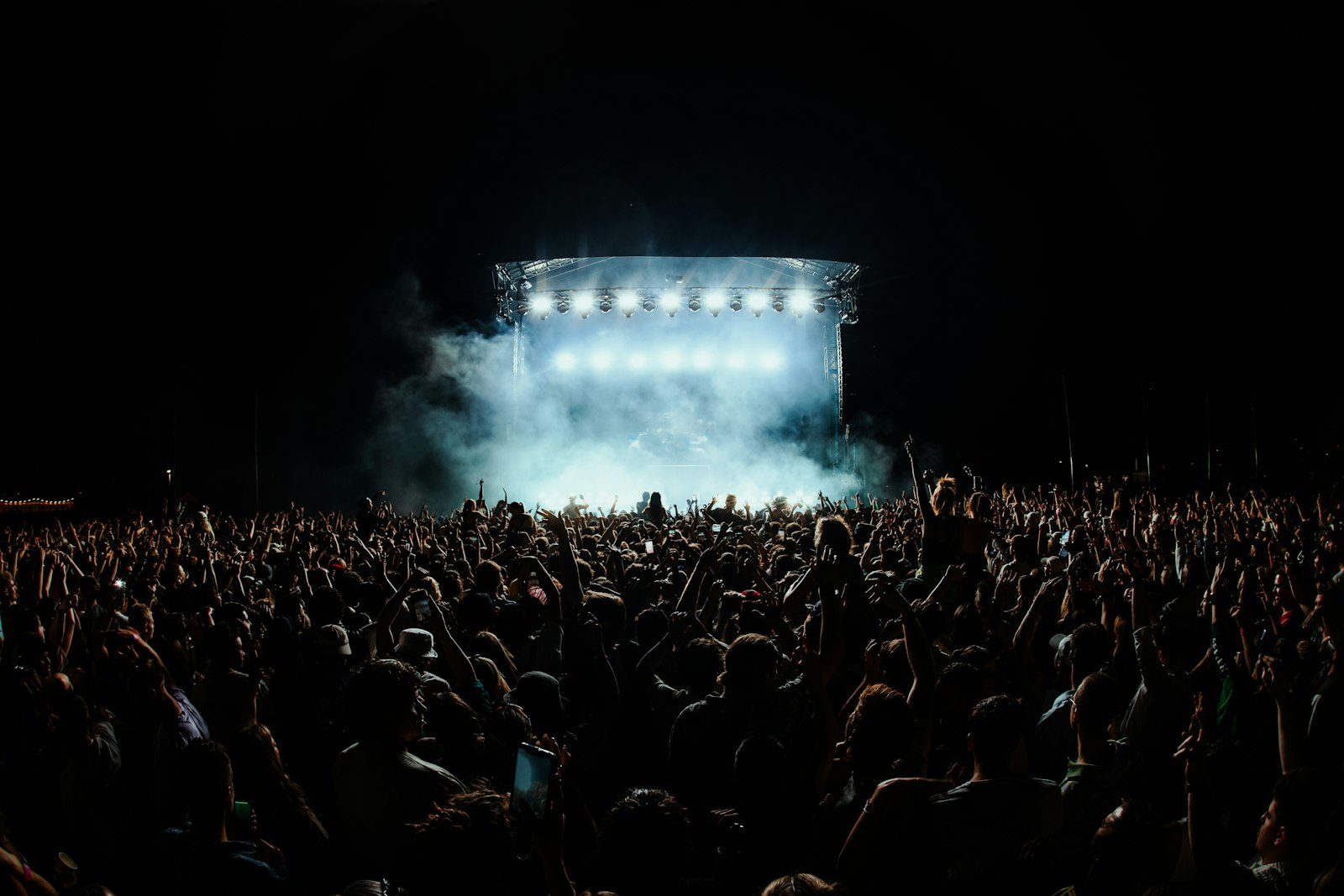 A large crowd facing a lit stage at night