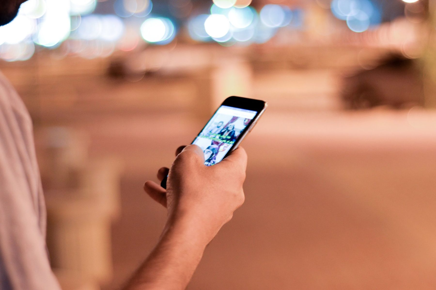 Hand scrolling through a video feed on a smartphone at night