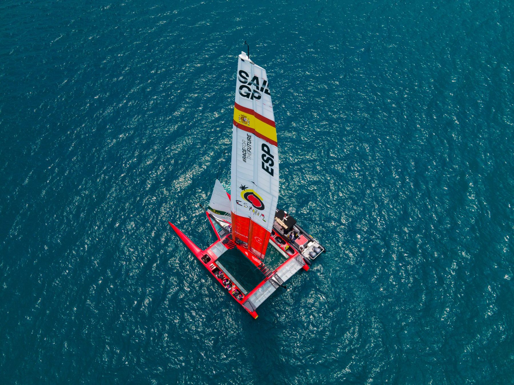 Aerial view looking down on the Spain F50 catamaran over blue water