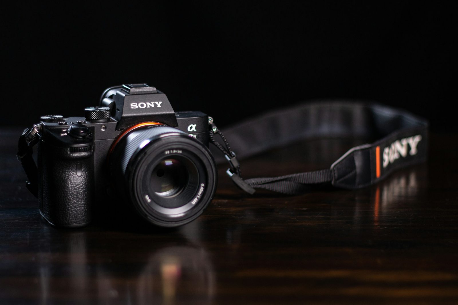 A Sony Alpha camera on a dark wooden desk in low light