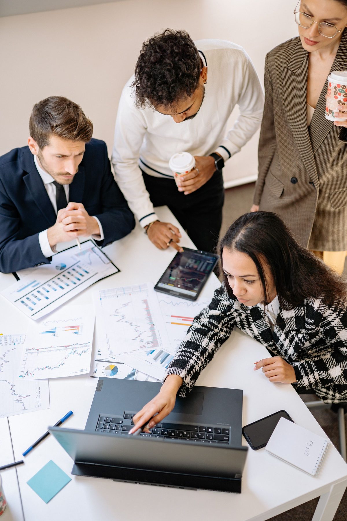Marketing team reviewing printed charts and a laptop around a white table