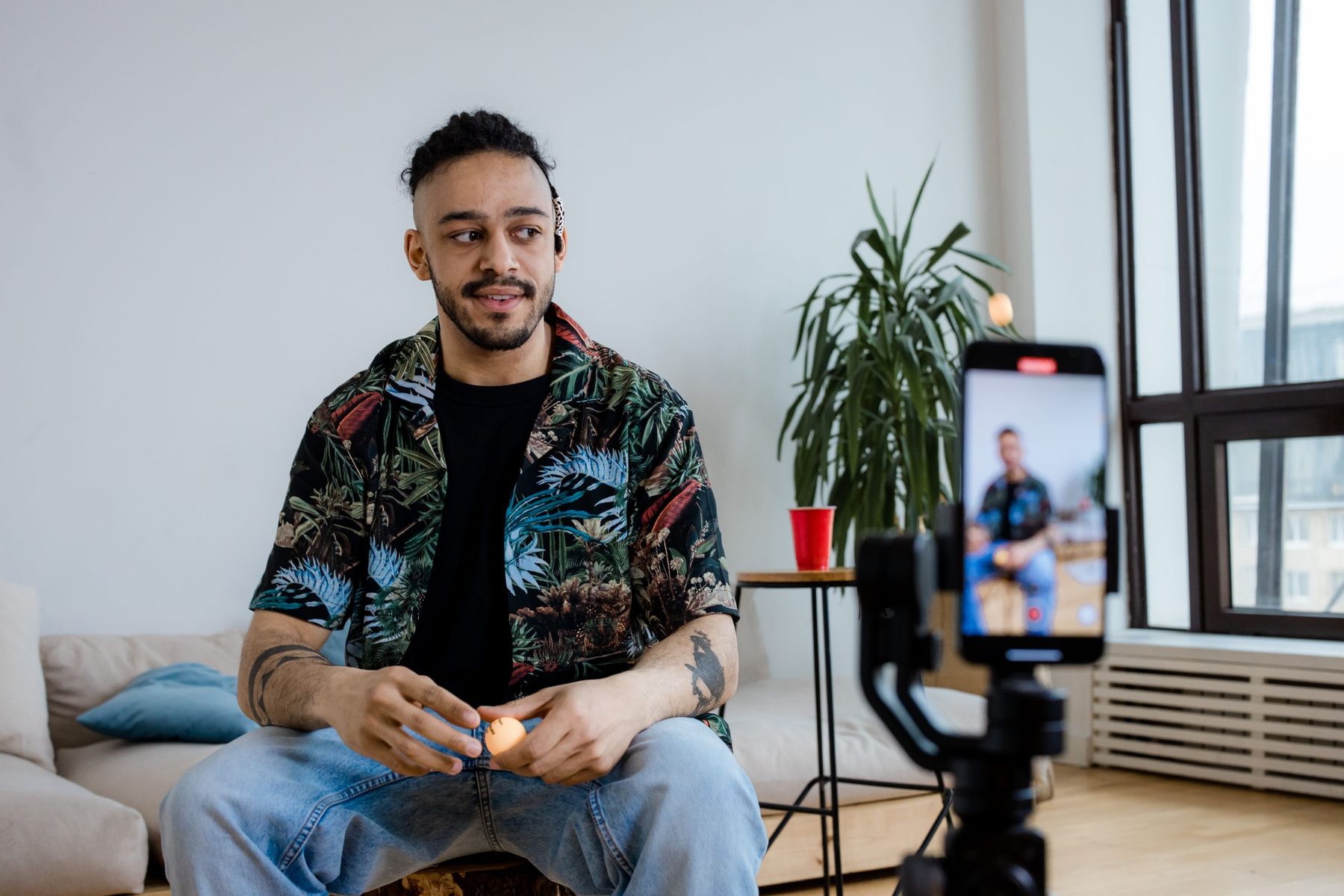 Young creator filming himself on a phone mounted on a gimbal in a bright flat