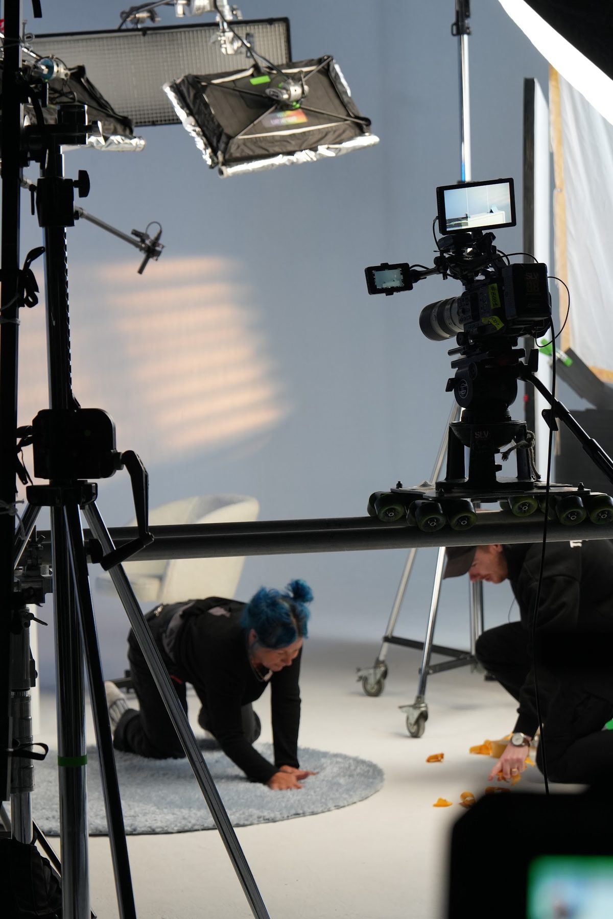 Cinema camera on a tripod with crew preparing a shot in a bright studio