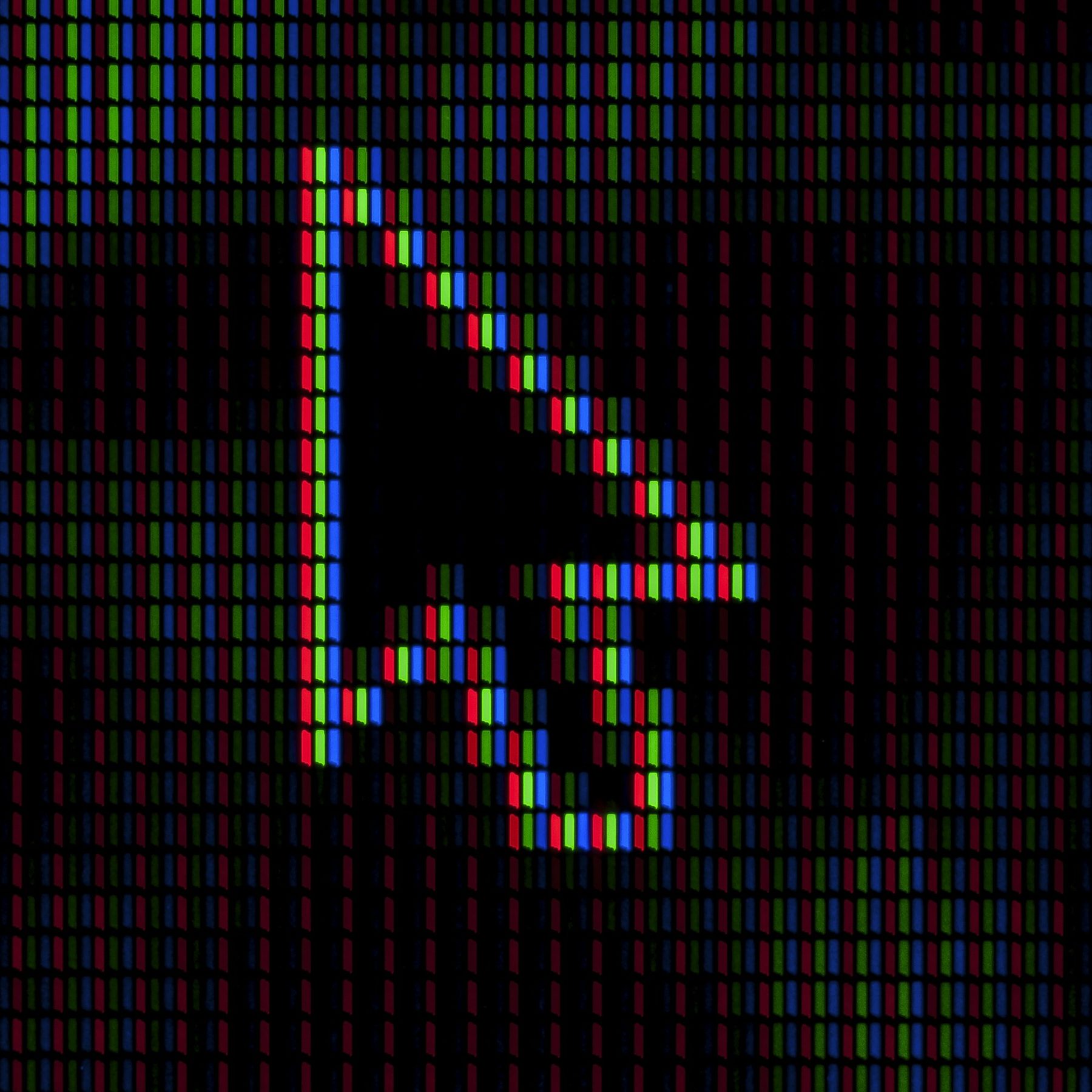 Macro photo of a computer cursor arrow made of red, green and blue screen pixels