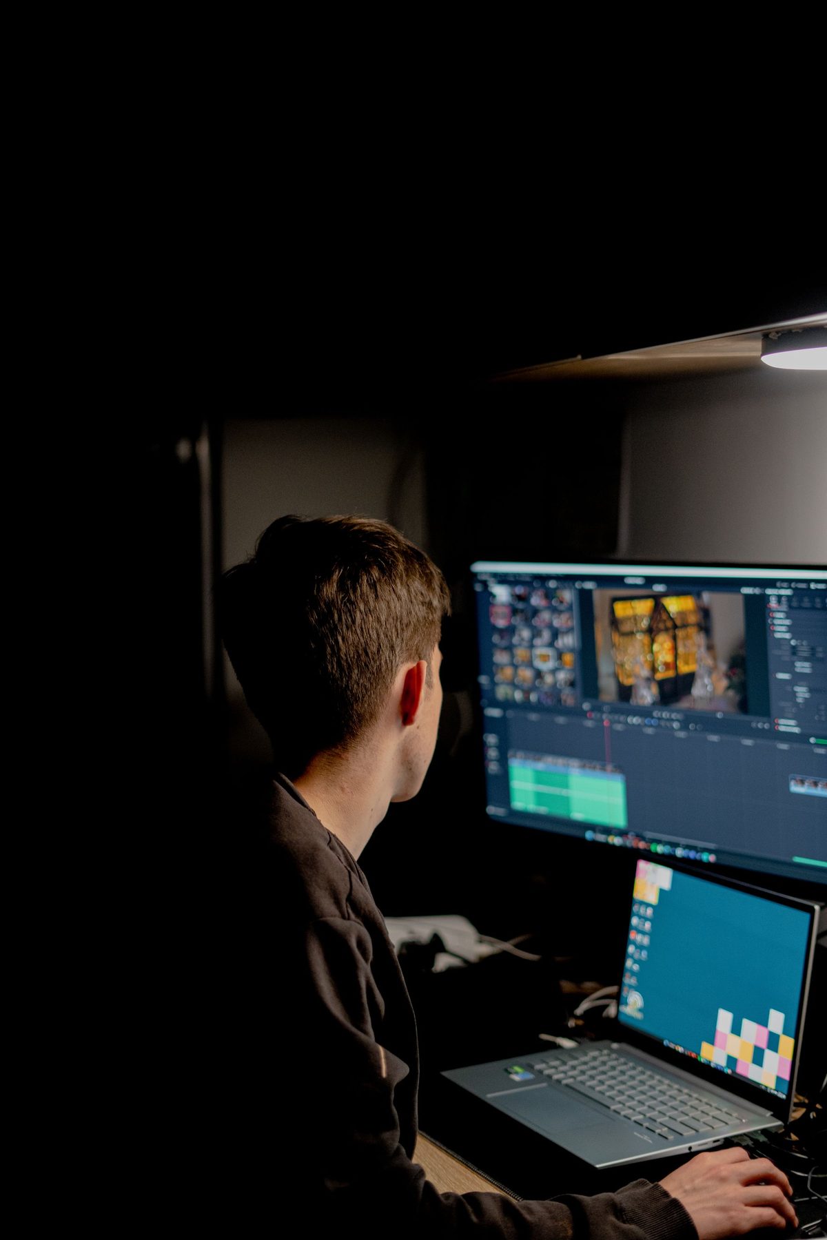 Video editor in a dark room cutting a timeline on a large monitor