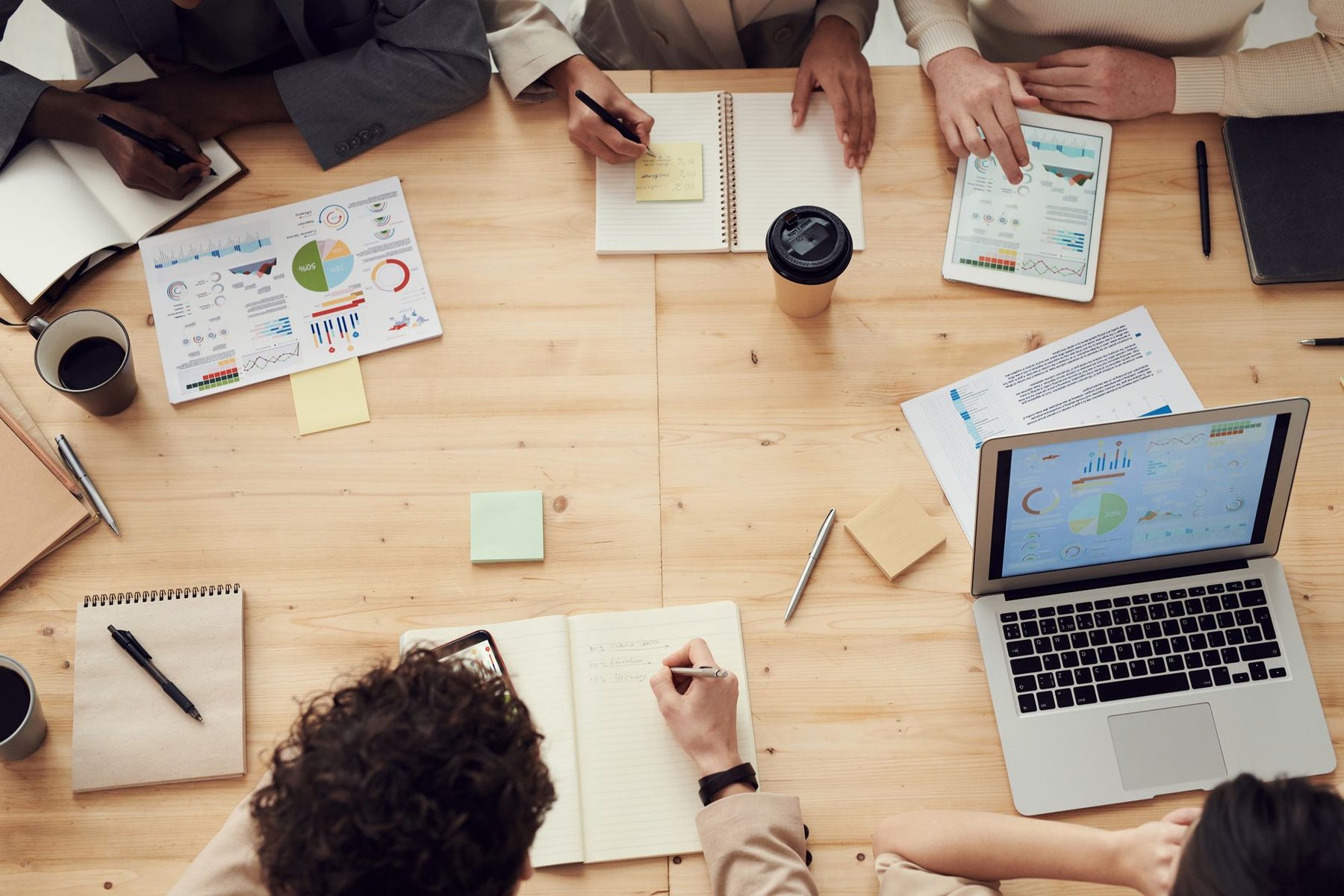 Overhead view of a team around a wooden table with notebooks and laptops planning content