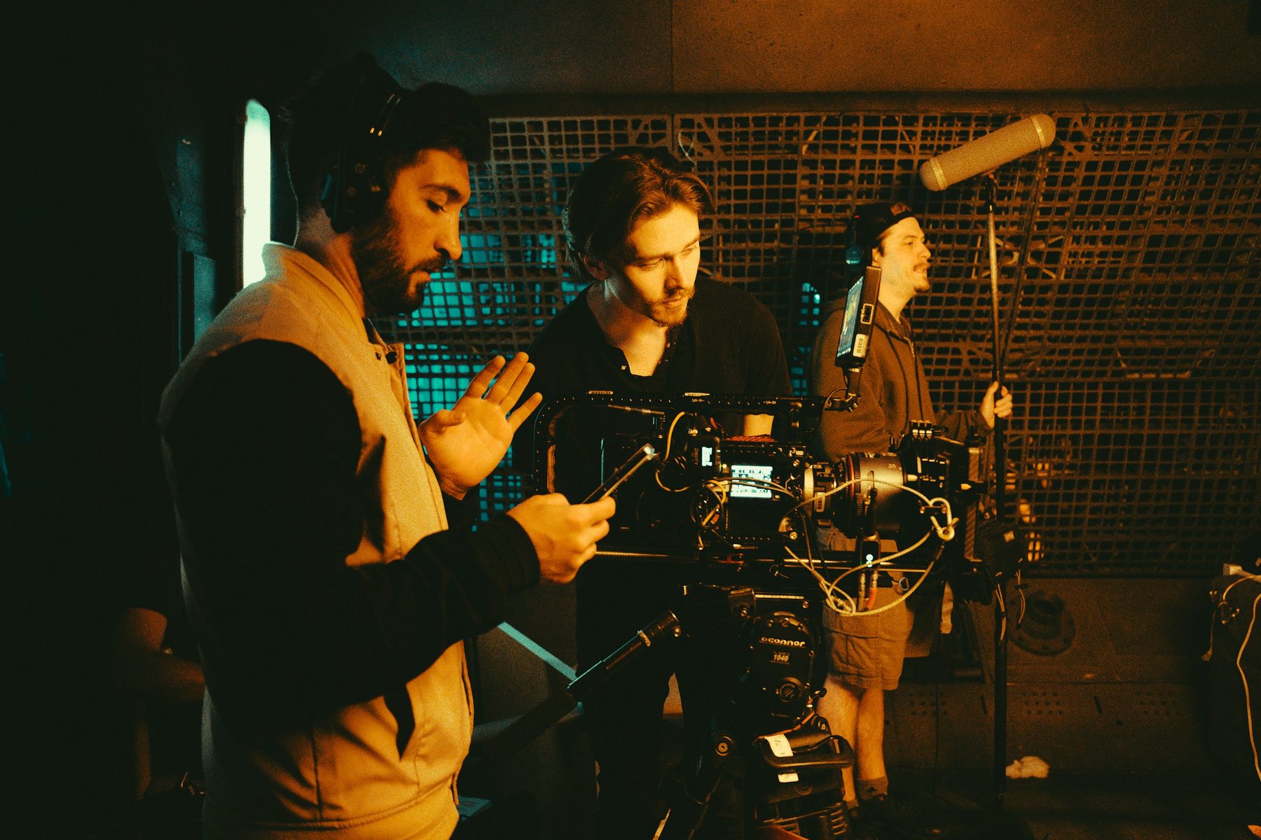 Small crew filming on location with a cinema camera and boom microphone in warm light