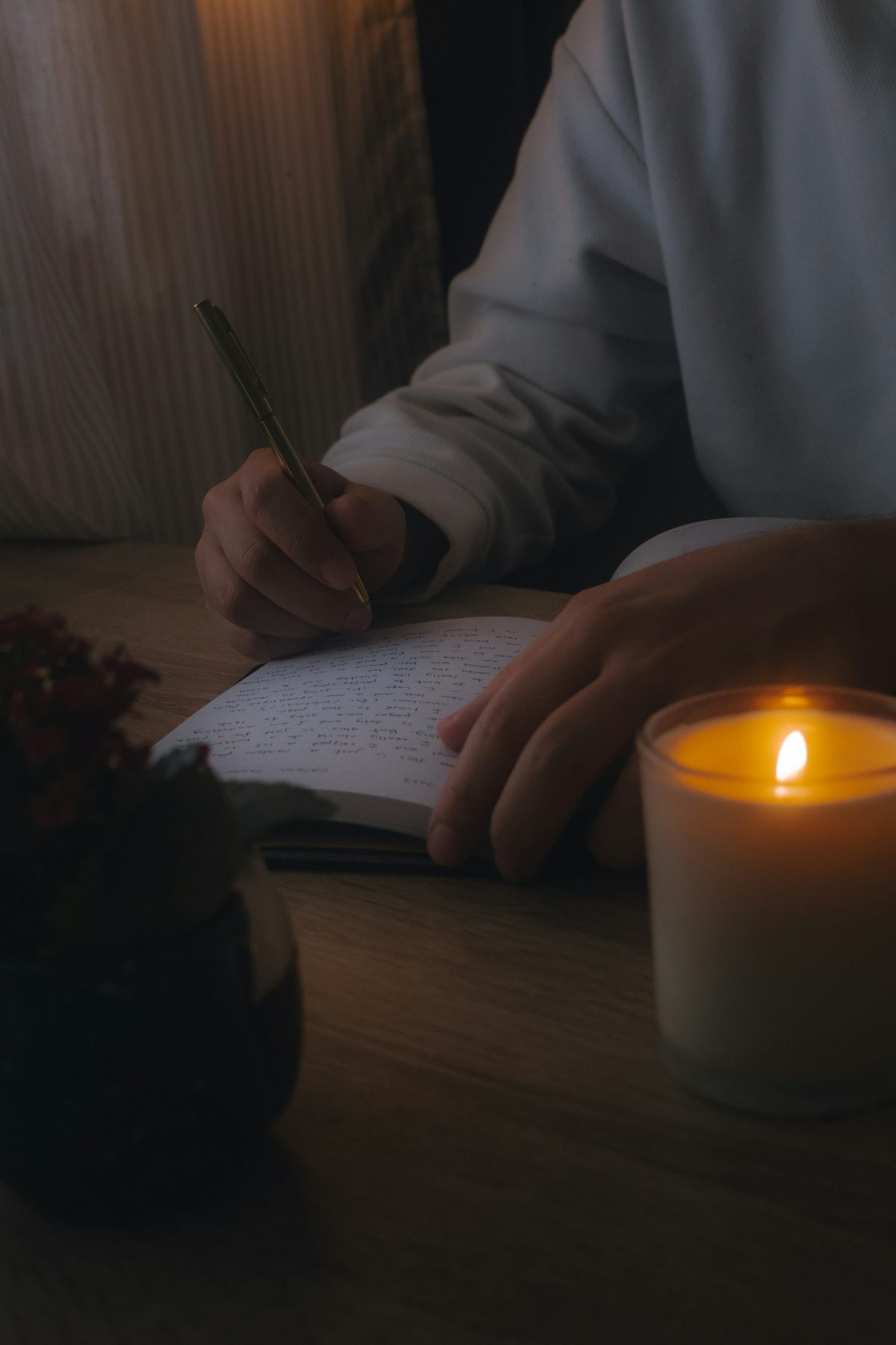 Person writing notes by candlelight while reviewing contract terms
