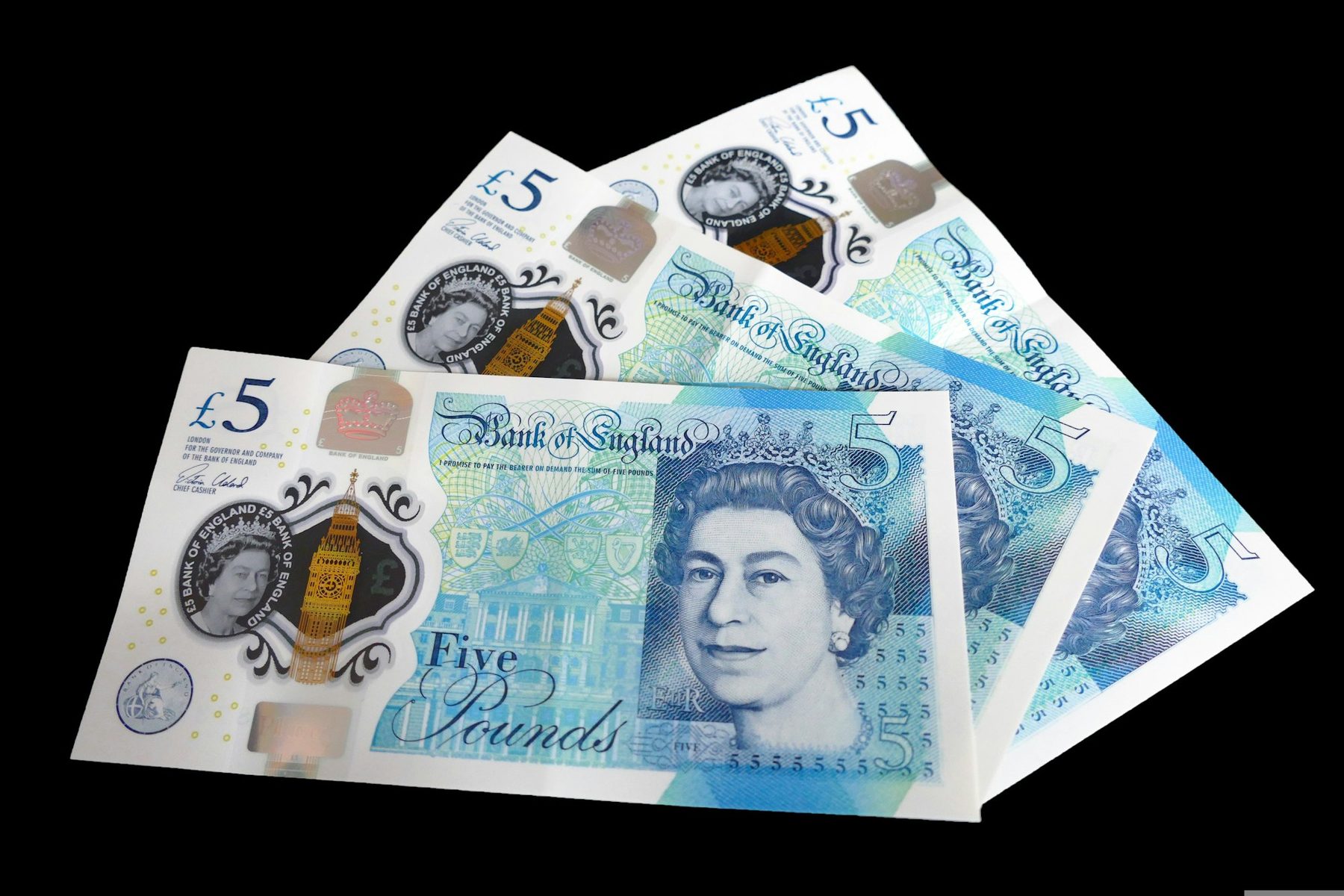 Fan of British five pound notes on a black background