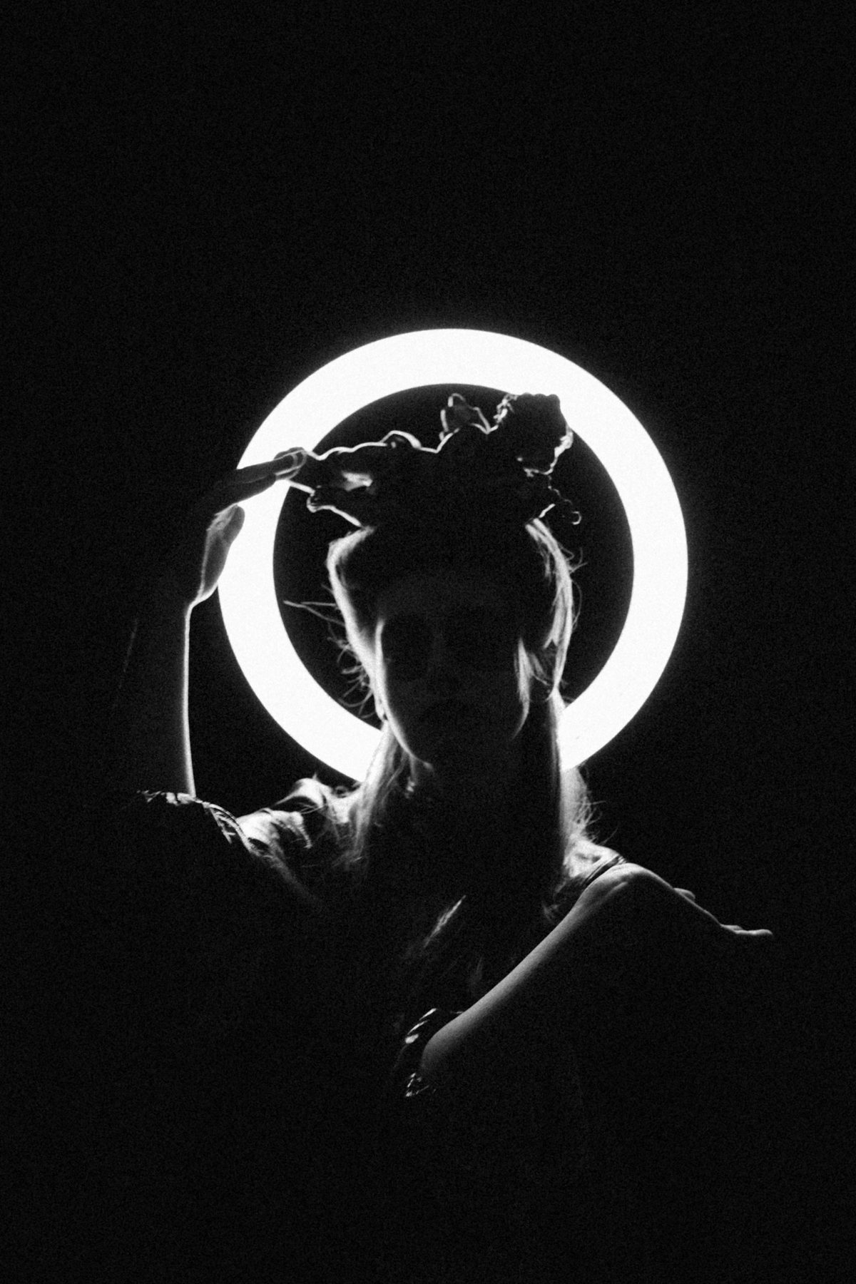 Silhouette of a person in front of a glowing ring light on a black background