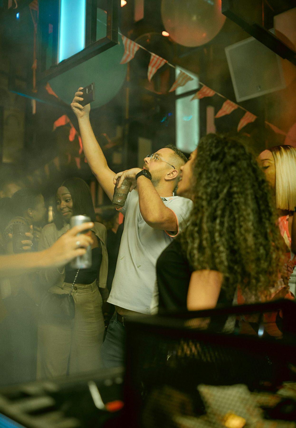 Group of friends taking a selfie on a phone at a dimly lit party