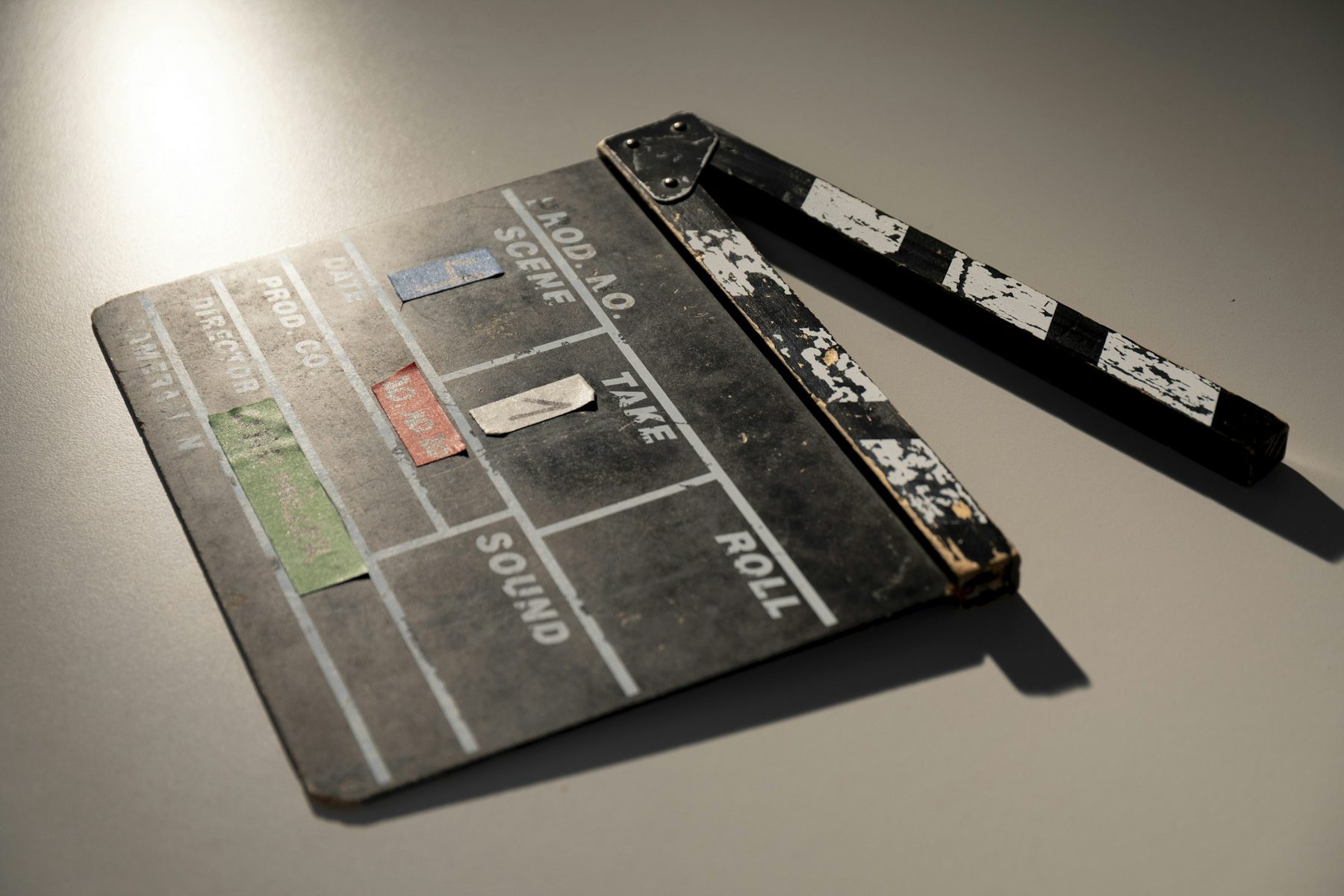 Worn film clapperboard resting on a grey surface in soft light