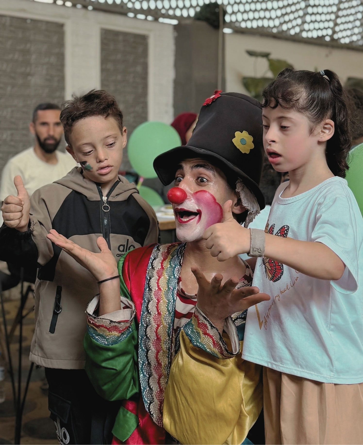 Ein Clown unterhält zwei Kinder bei einer Veranstaltung.