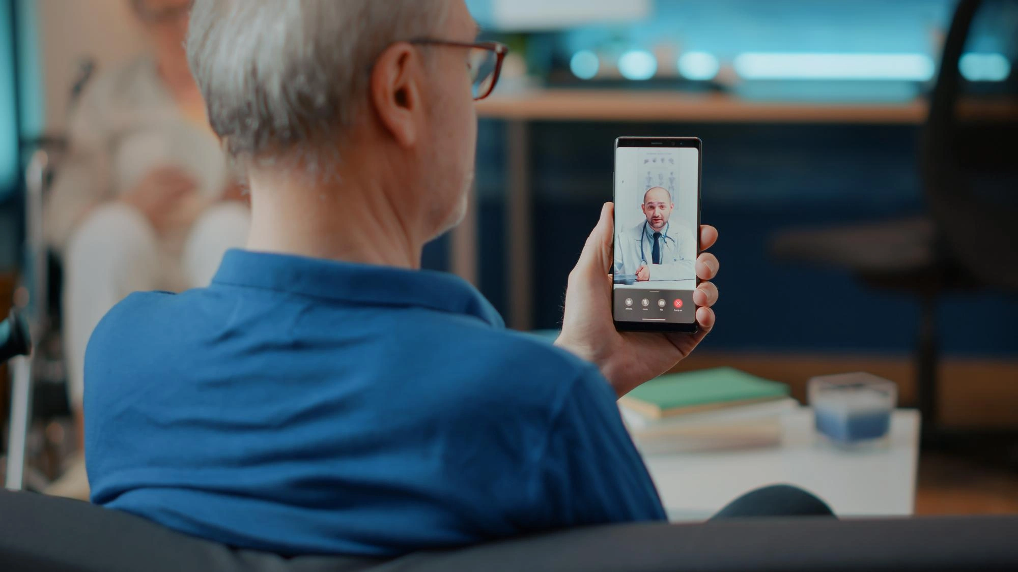 Senior man holding a smartphone video call with a doctor