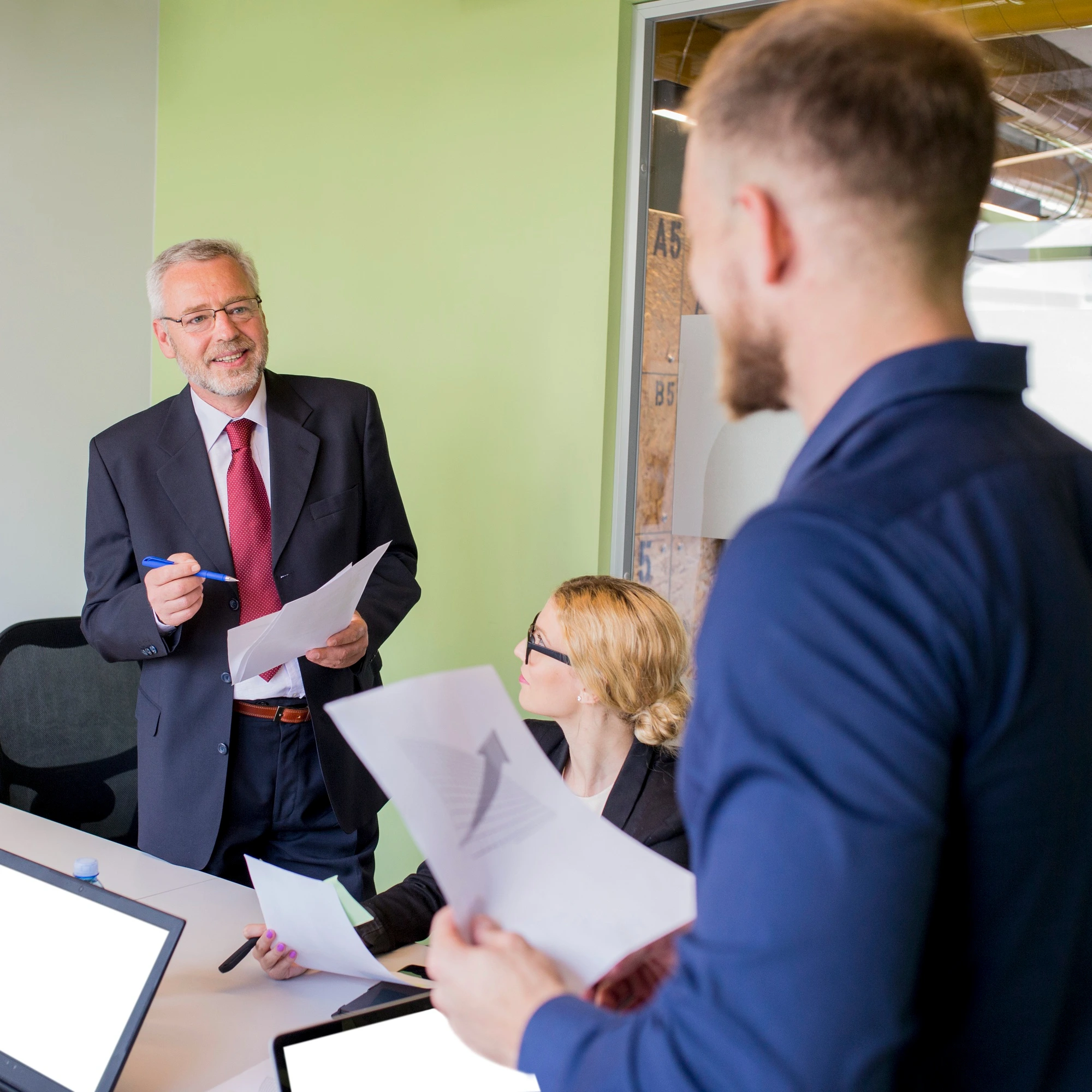 Business team in a meeting with one person standing and holding documents