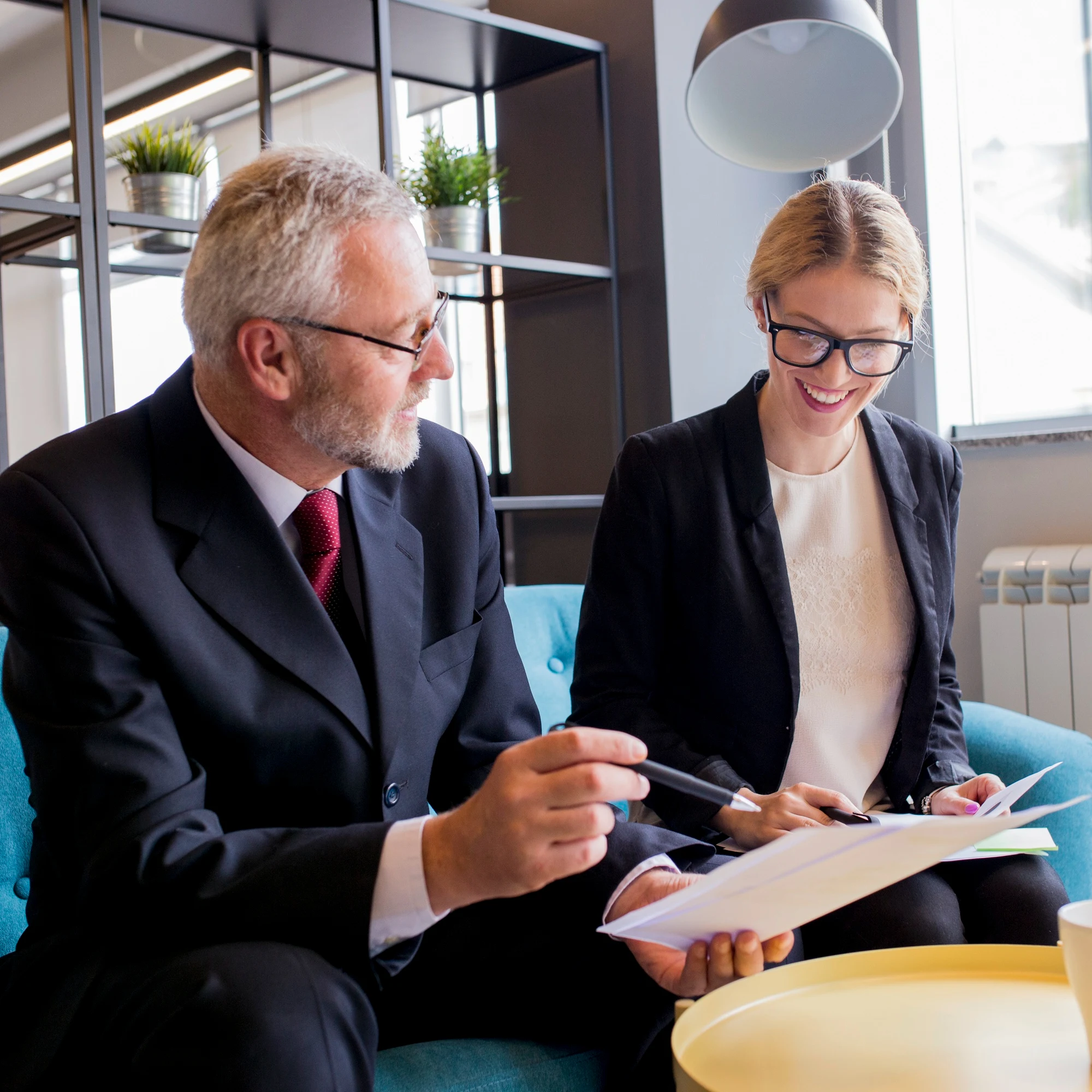 Older man and woman in business attire reviewing documents together