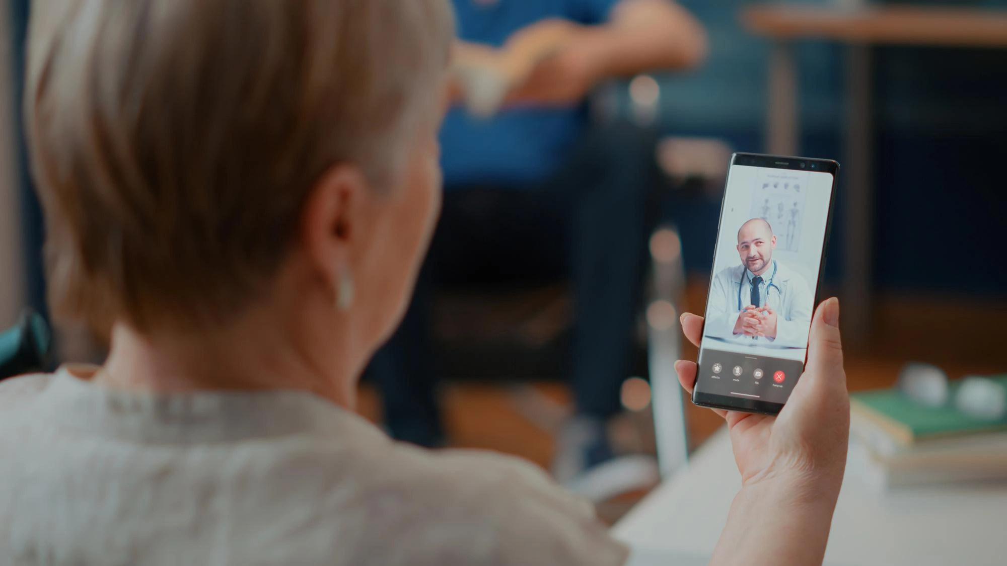 Older woman on a smartphone video call with a doctor