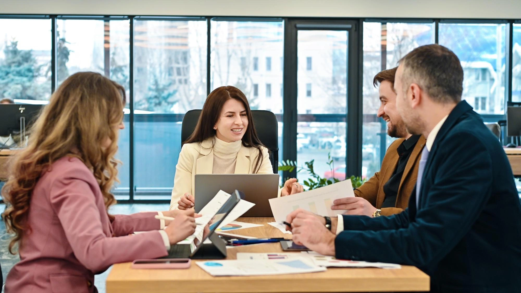Team of professionals meeting around a table with documents and laptops