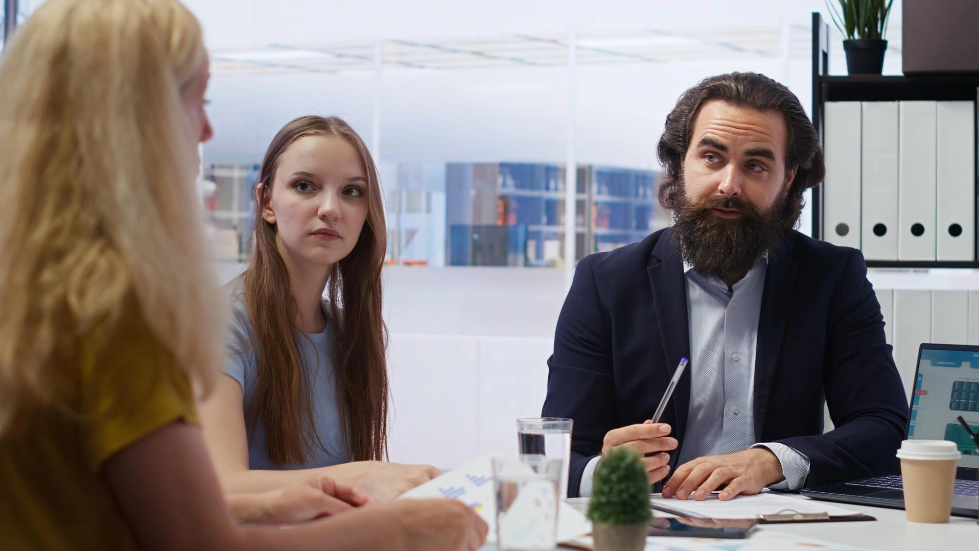 Man in a suit talking with two colleagues at a business meeting