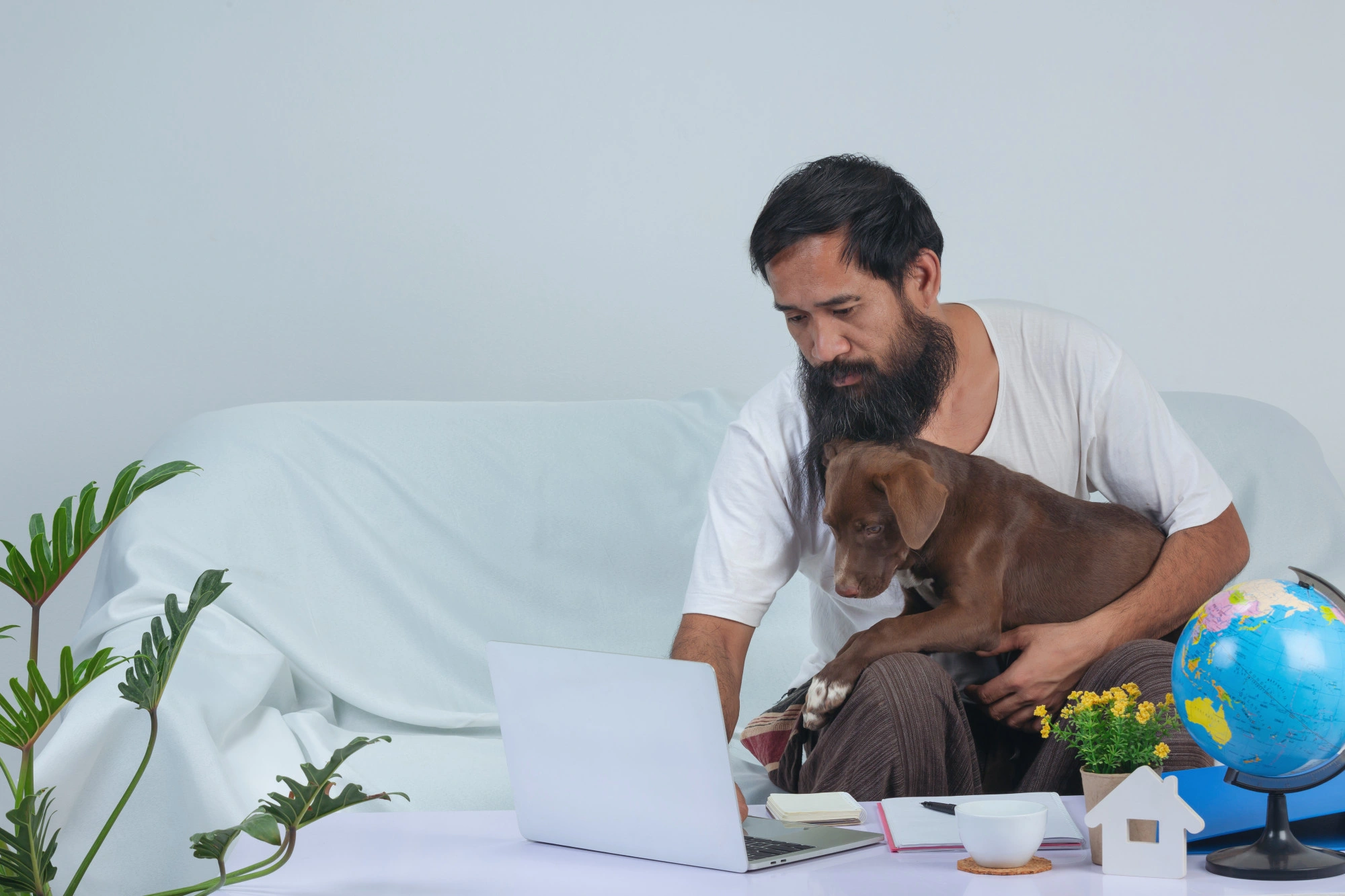 Man working on a laptop at home with his dog on his lap