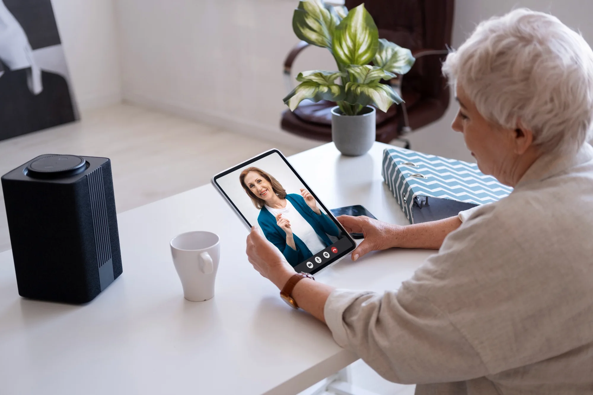 Older woman on a tablet video call with a female doctor at home