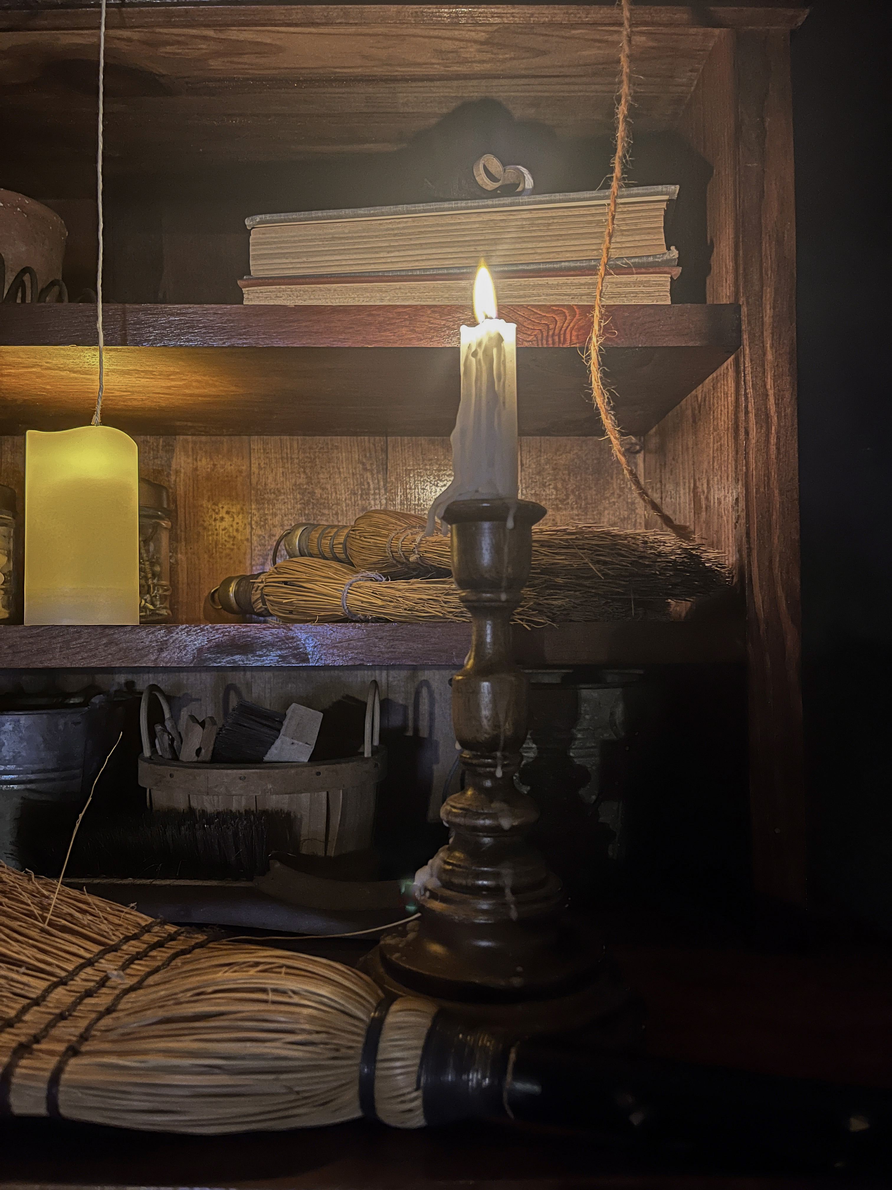 Lit taper candle and vintage objects on a dark wooden workshop table