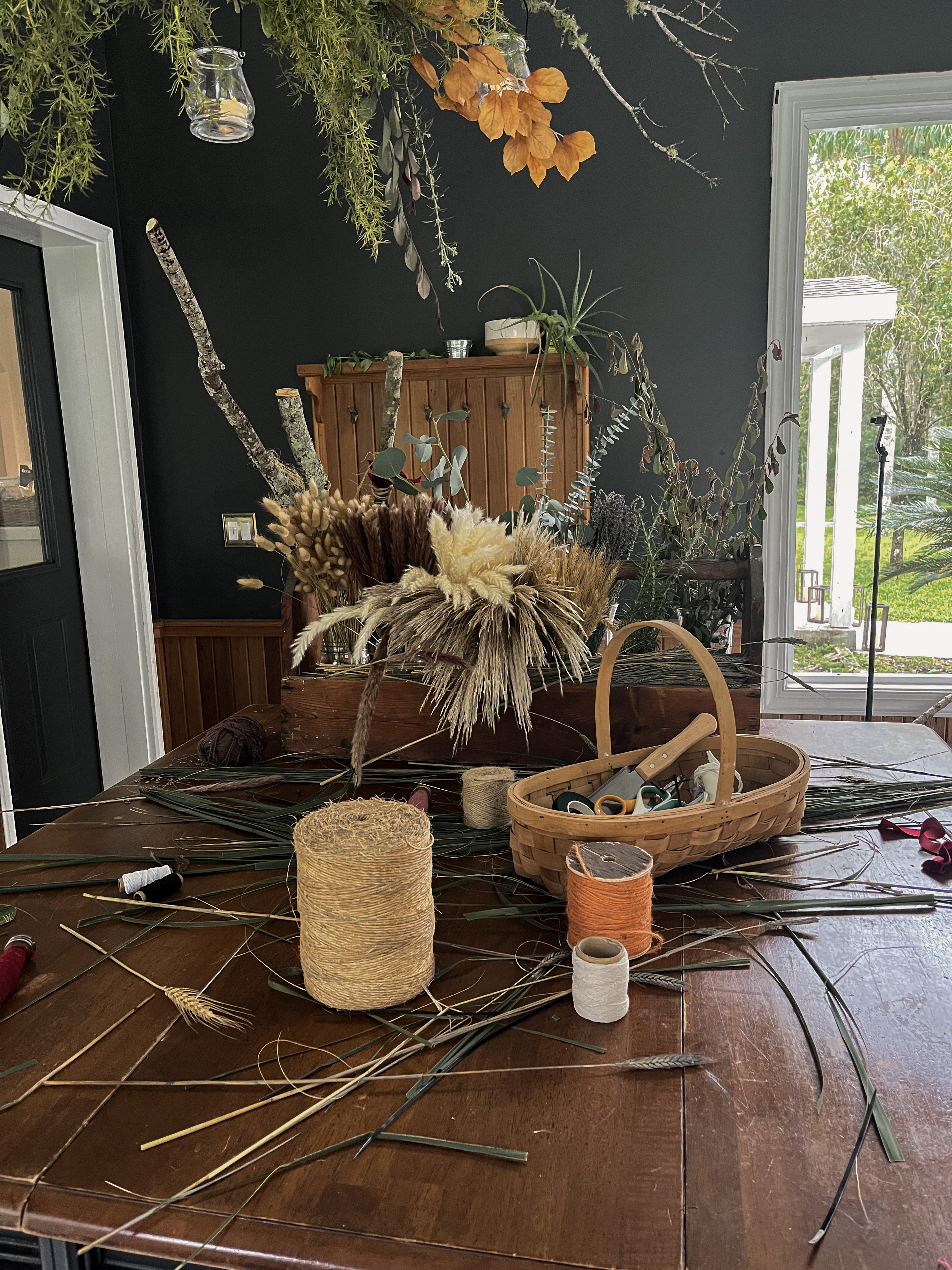Broom-making materials, tools and dried botanicals covering the workshop table