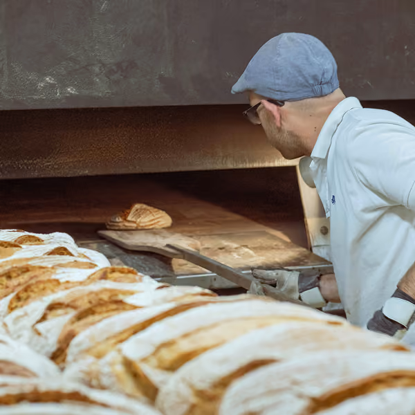 a baker pulls a finished loaf out of an oven
