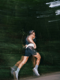 Runner in motion on a forest trail, shown with motion blur
