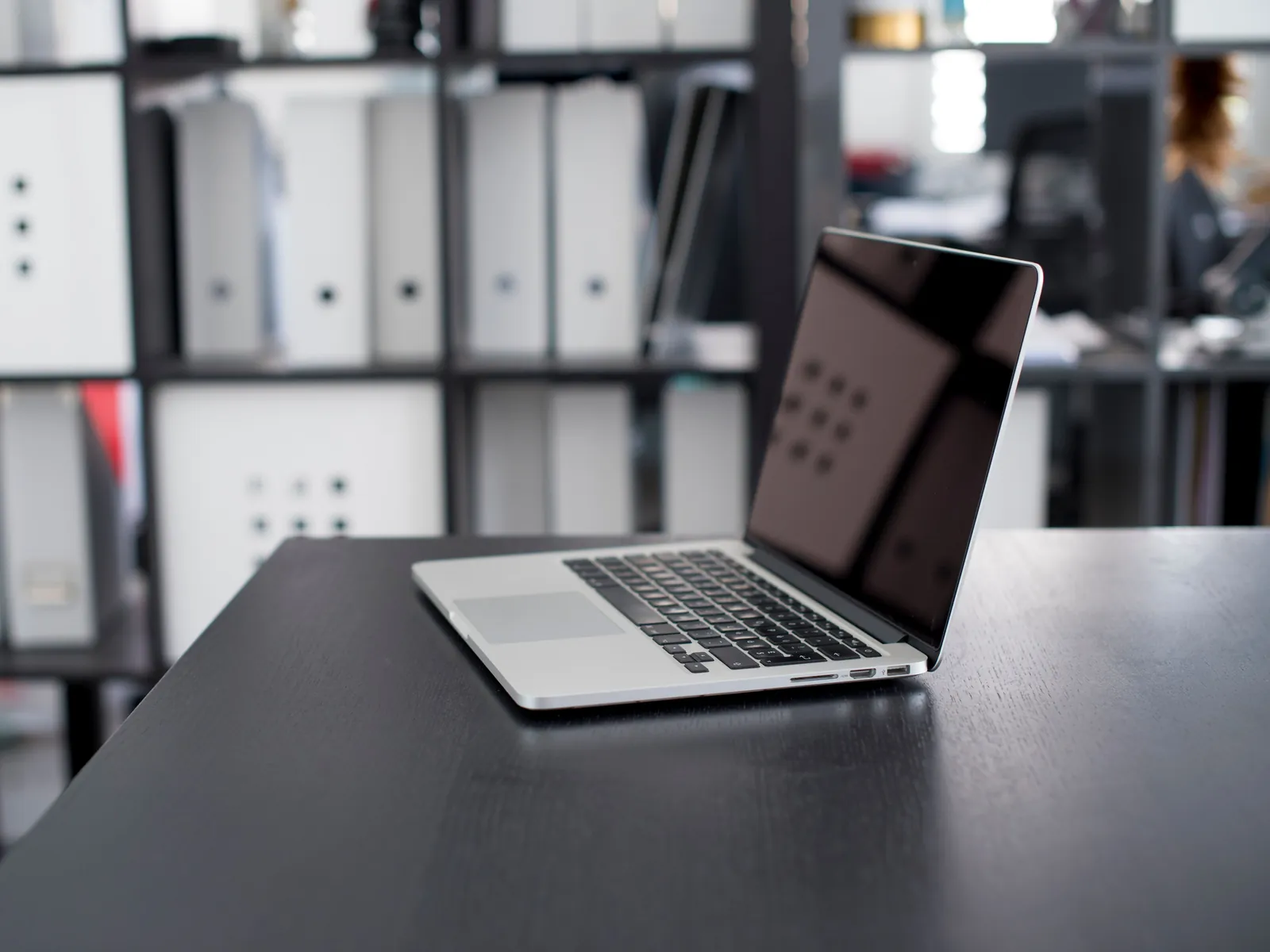 Ordinateur portable sur un bureau rangé, devant des classeurs alignés