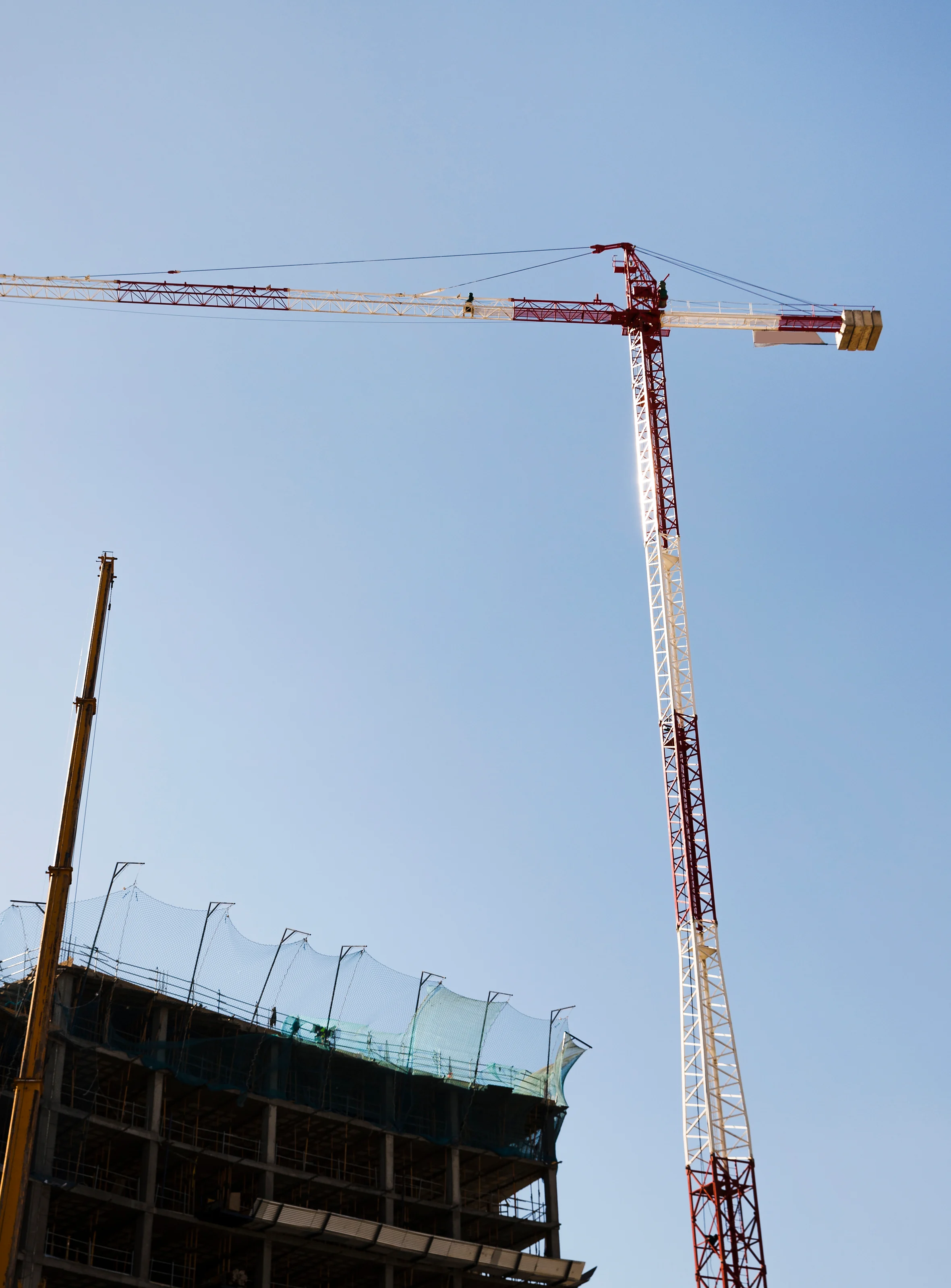 Grue rouge et blanche au-dessus d'un immeuble en chantier