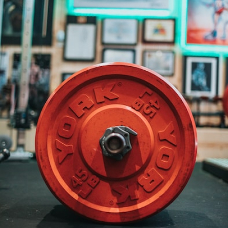 Red barbell plate in a fully equipped gym