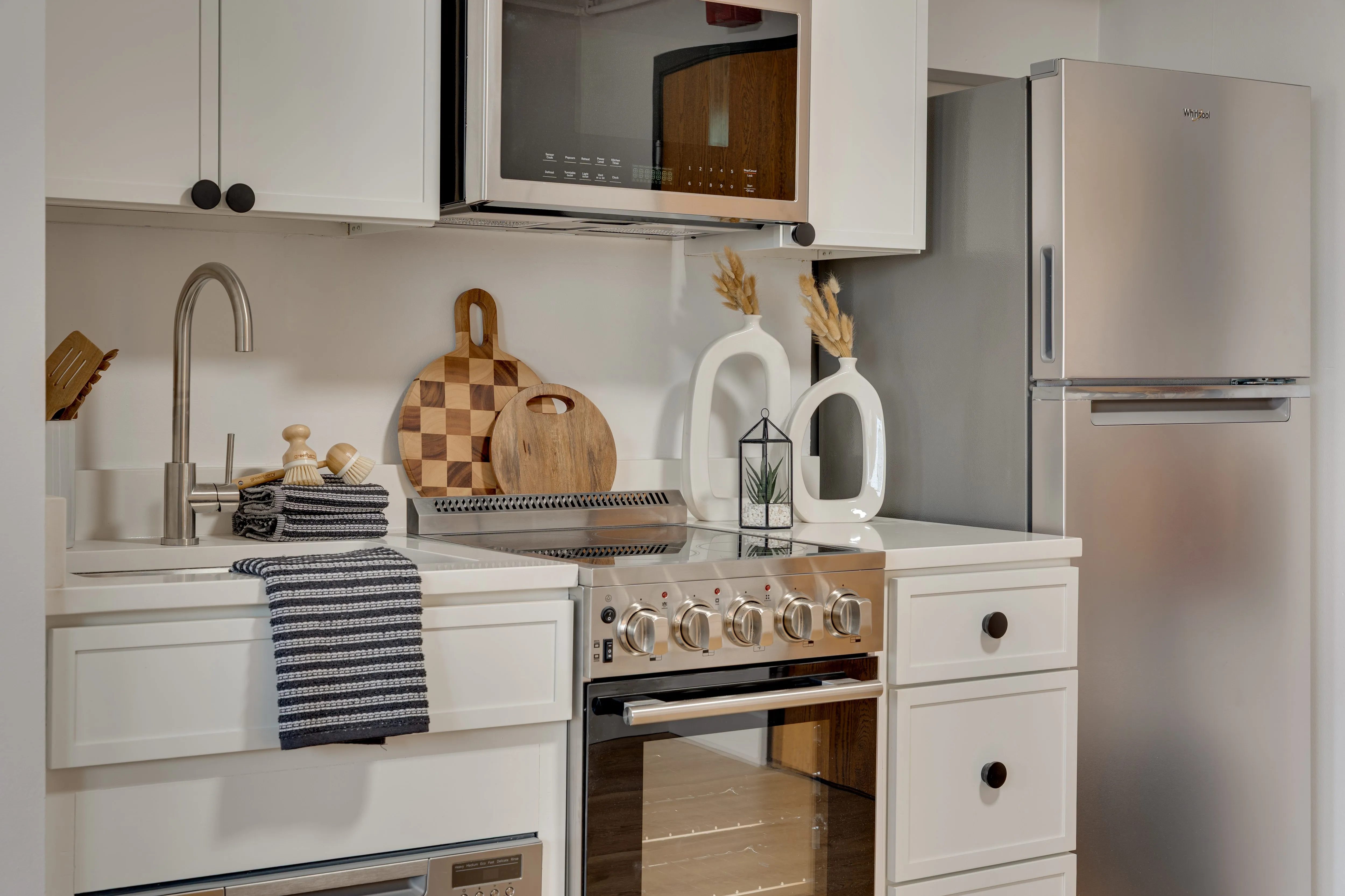 Buckner apartment kitchen with white cabinets, stainless range, refrigerator and over-range microwave