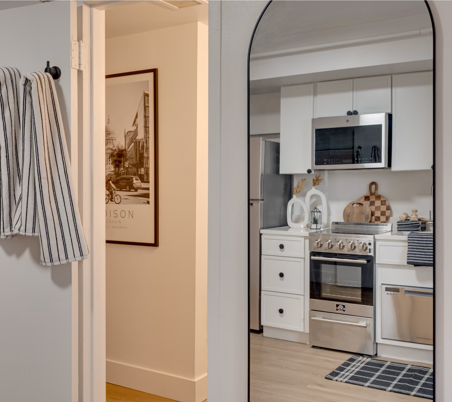 View through an arched mirror into a Buckner apartment kitchen with white cabinets and stainless appliances