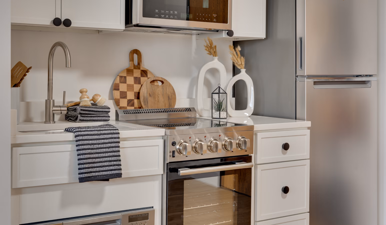 Buckner apartment kitchen with white cabinets, stainless range and over-range microwave