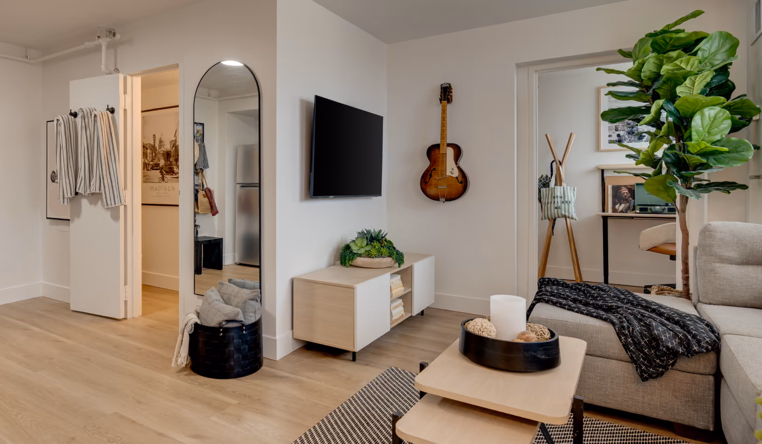Furnished Buckner living room with a sectional, wall-mounted TV, media console and arched mirror