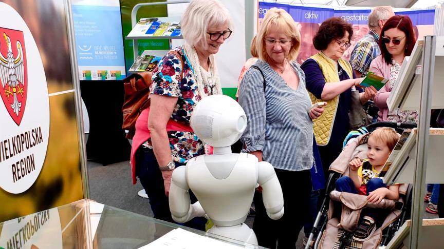 Visitors gather around Pepper at the Wielkopolska Region stand at Hessentag, including a toddler in a pushchair