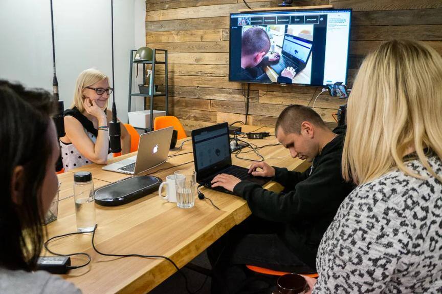 A tester uses a laptop while the Snowdog team watches his screen mirrored on a wall monitor