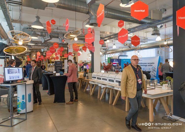 Networking area at Concordia Design Center decorated with orange hanging hexagons and #mm16pl signs